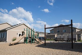 a playground with a slide and monkey bars in front of a building